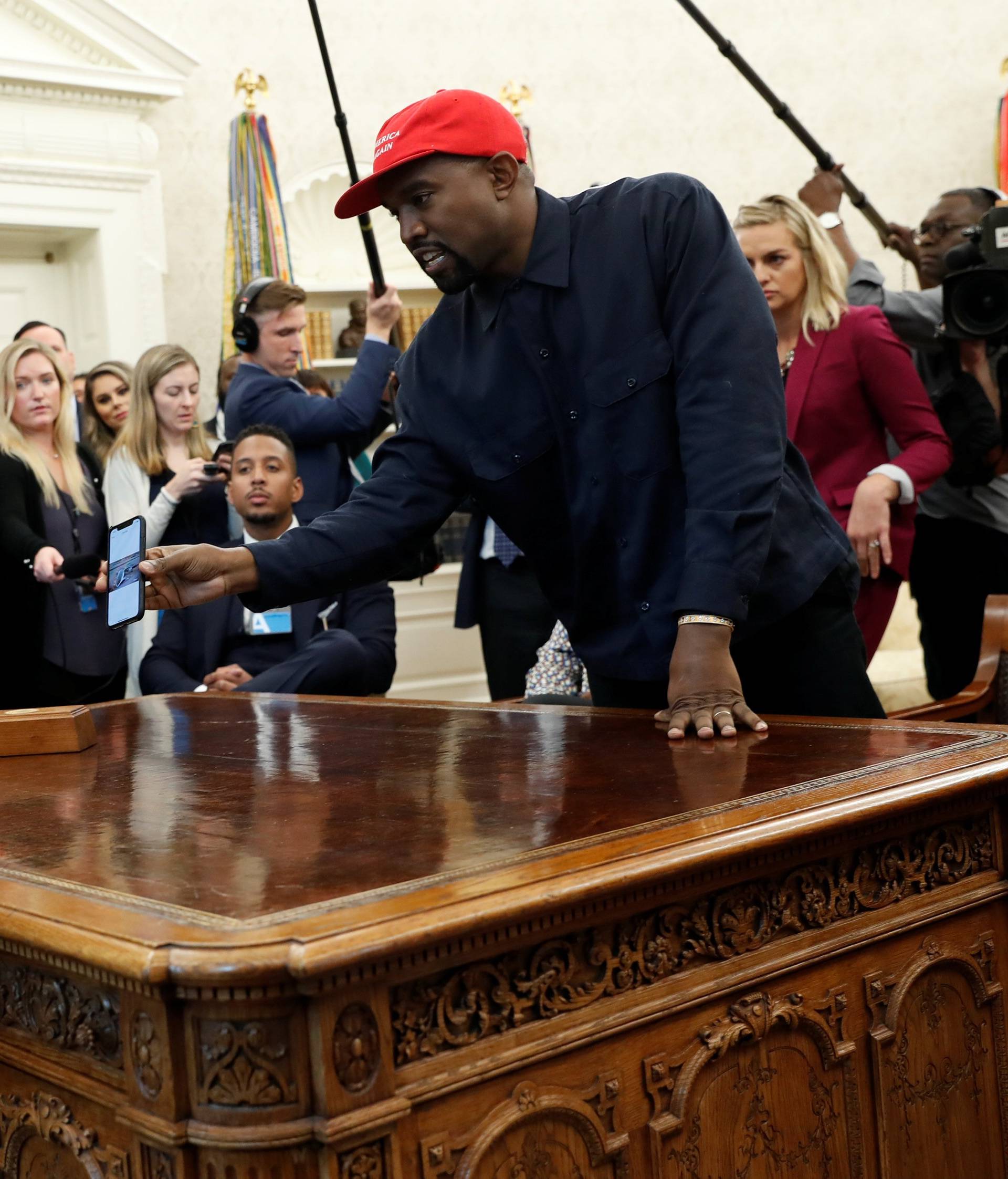 Rapper Kanye West shows President Trump his mobile phone during meeting in the Oval Office at the White House in Washington