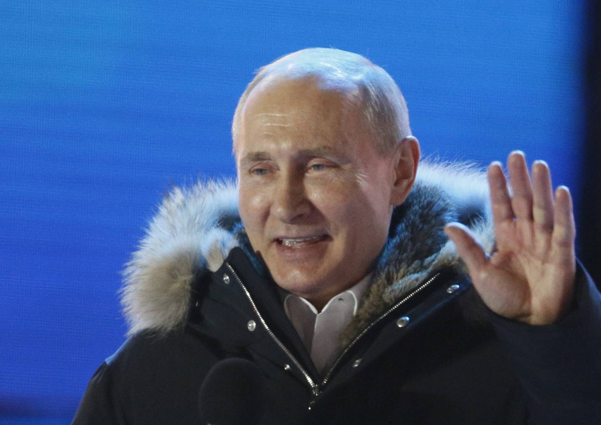 Russian President and Presidential candidate Putin gestures as he attends a rally and concert marking the fourth anniversary of Russia's annexation of the Crimea region, in Moscow