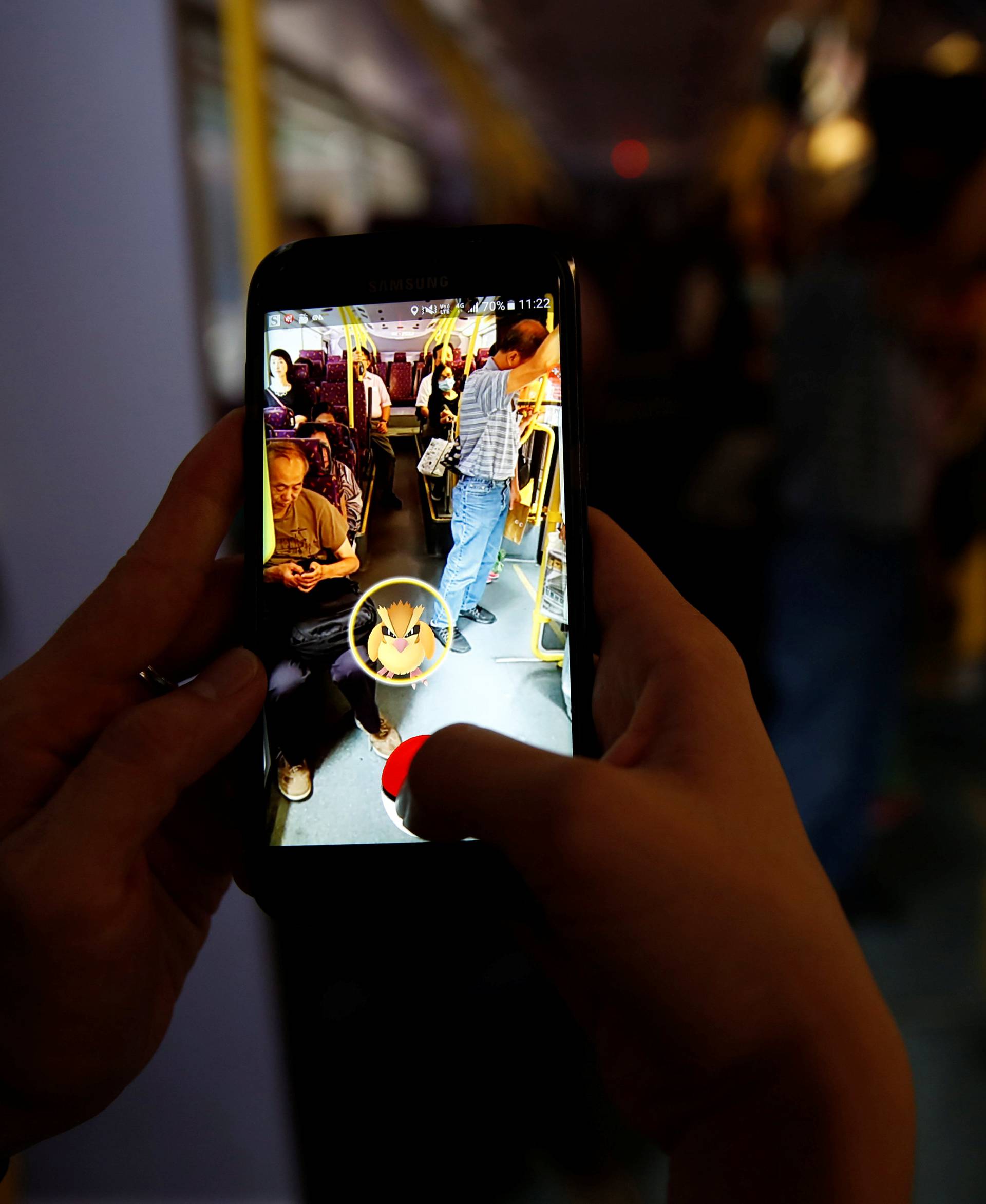 A passenger plays the augmented reality mobile game "Pokemon Go" by Nintendo inside a bus in Hong Kong, China 