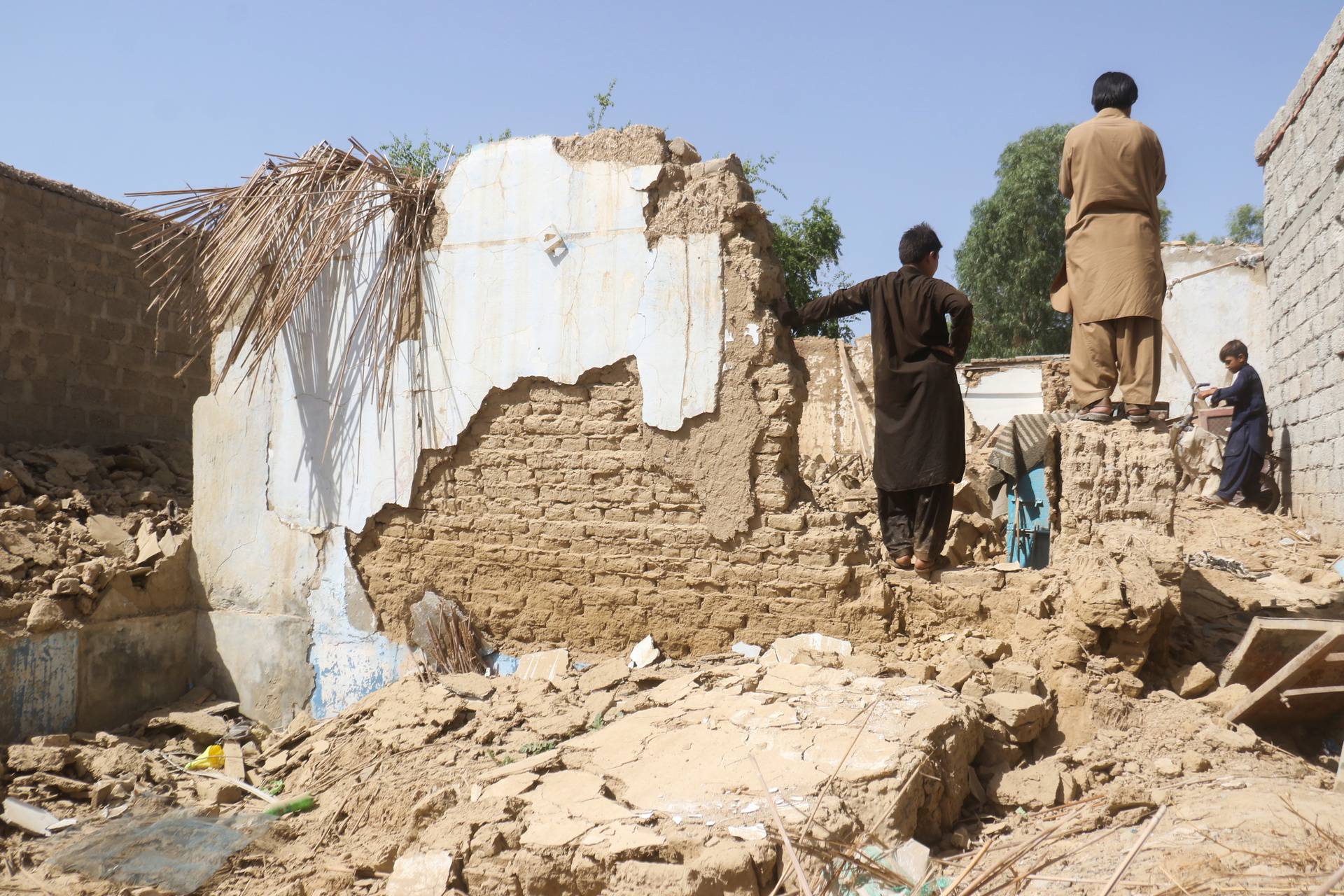 Residents stand amid the rubble of a damaged house following an earthquake in Harnai