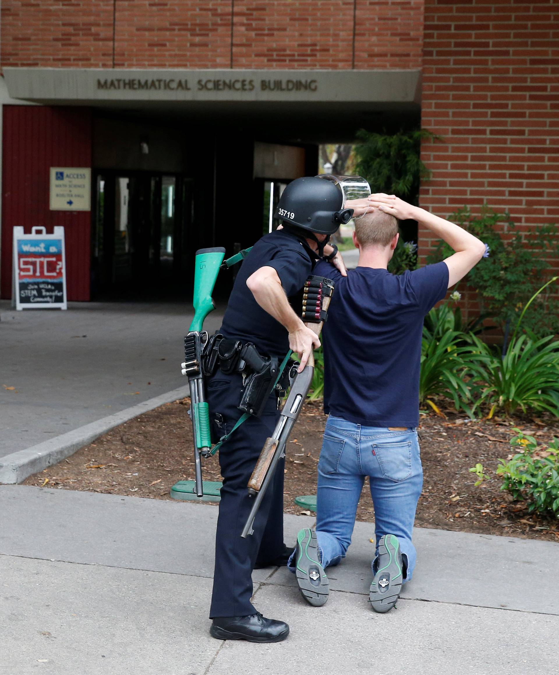 A police officer searches a student at the University of California, Los Angeles campus after it was placed on lockdown following reports of a shooter on the campus in Los Angeles