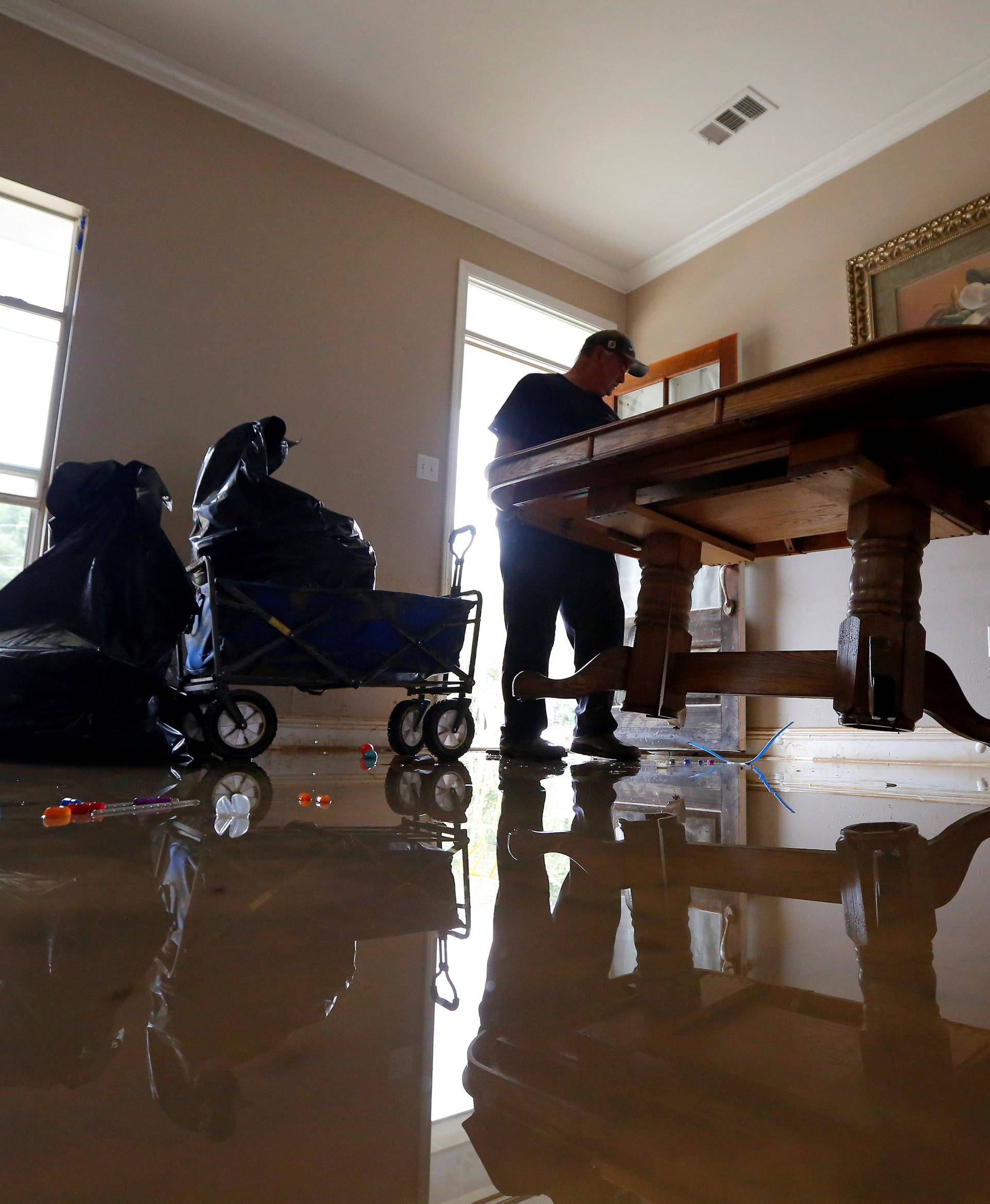 Clay Tassin and Pete Hildebrand remove a flood damaged dining table out of their coworker's house in Denham Springs