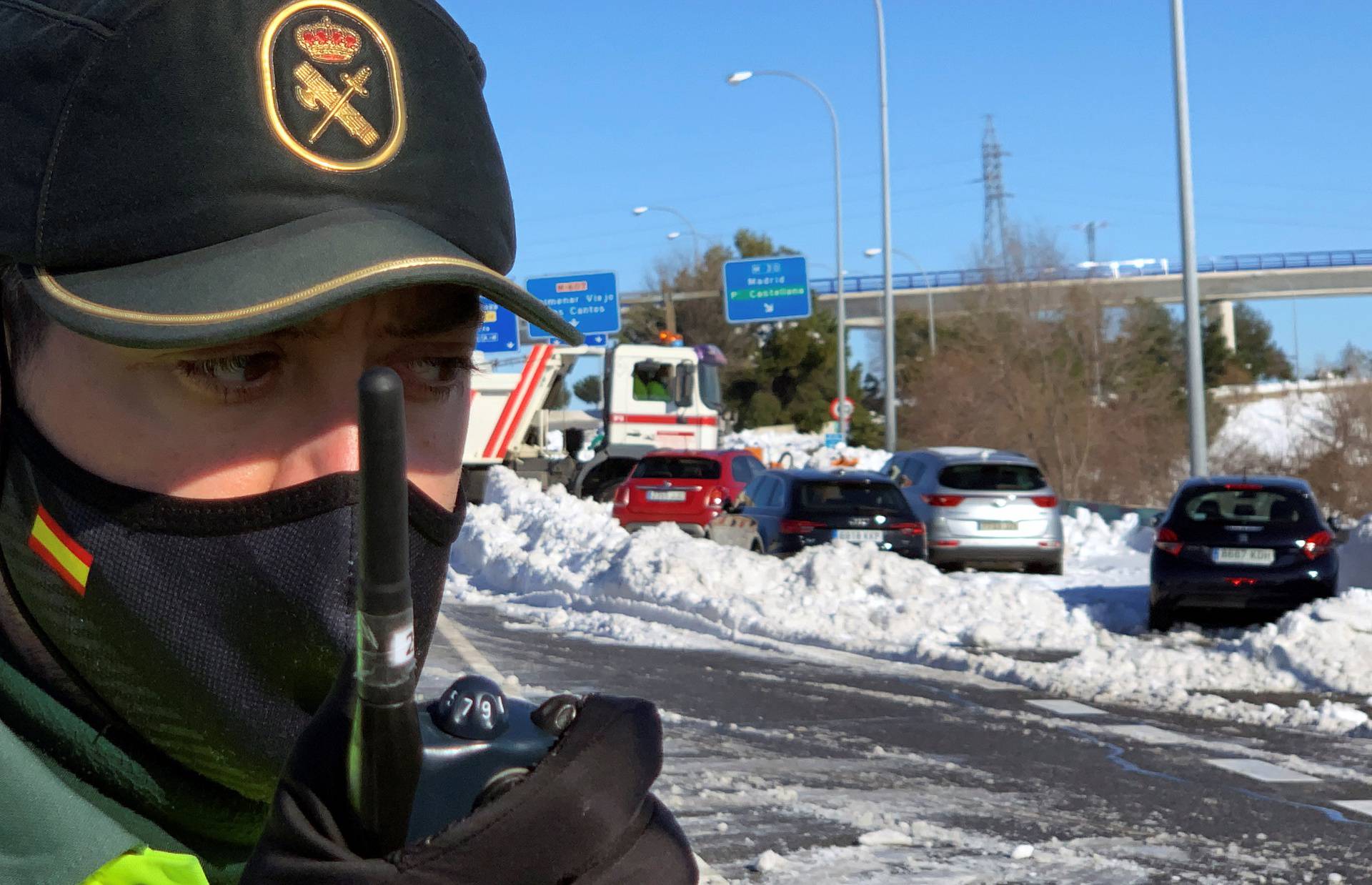 A Spanish Civil Guard talks on his walkie talkie in front of cars accumulated on M-40 highway after heavy snowfall in Madrid