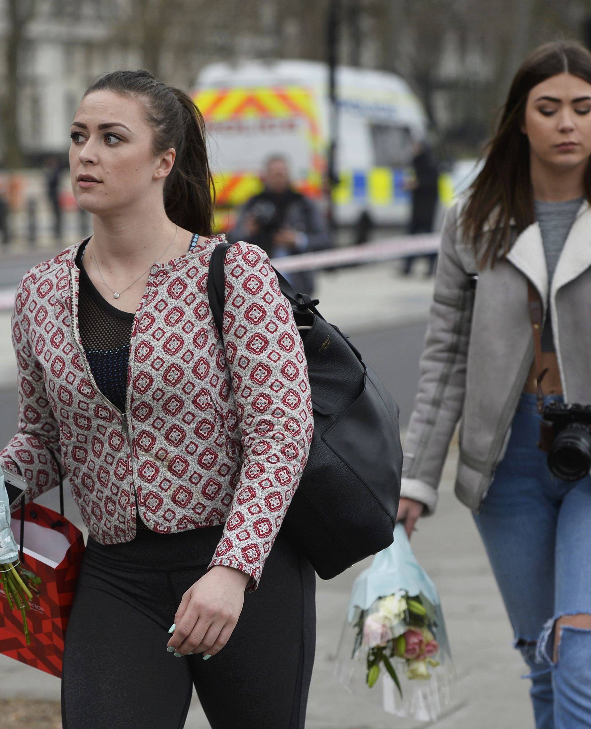 Two women carry flowers as they walk alongside the police cordon the morning after an attack in London
