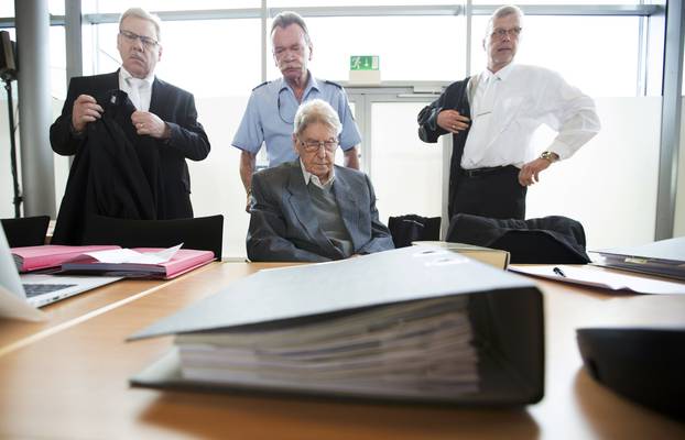 Defendant Hanning, a 94-year-old former guard at Auschwitz death camp, sits in a courtroom as his lawyers Scharmer and Salmen stand next to him before his trial in Detmold