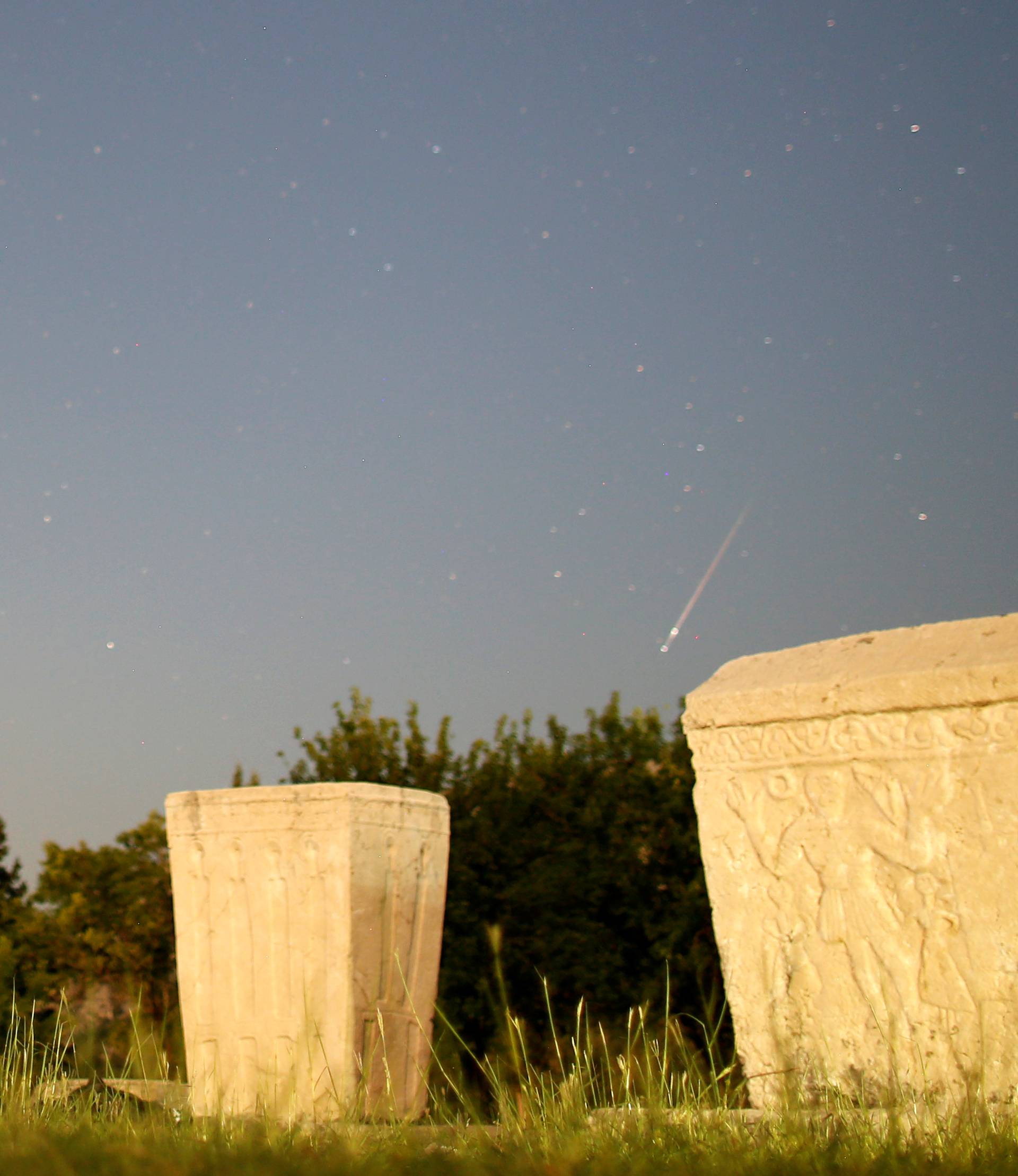 A meteor streaks past stars in the night sky above medieval tombstones during the Perseid meteor shower in Radimlja near Stolac