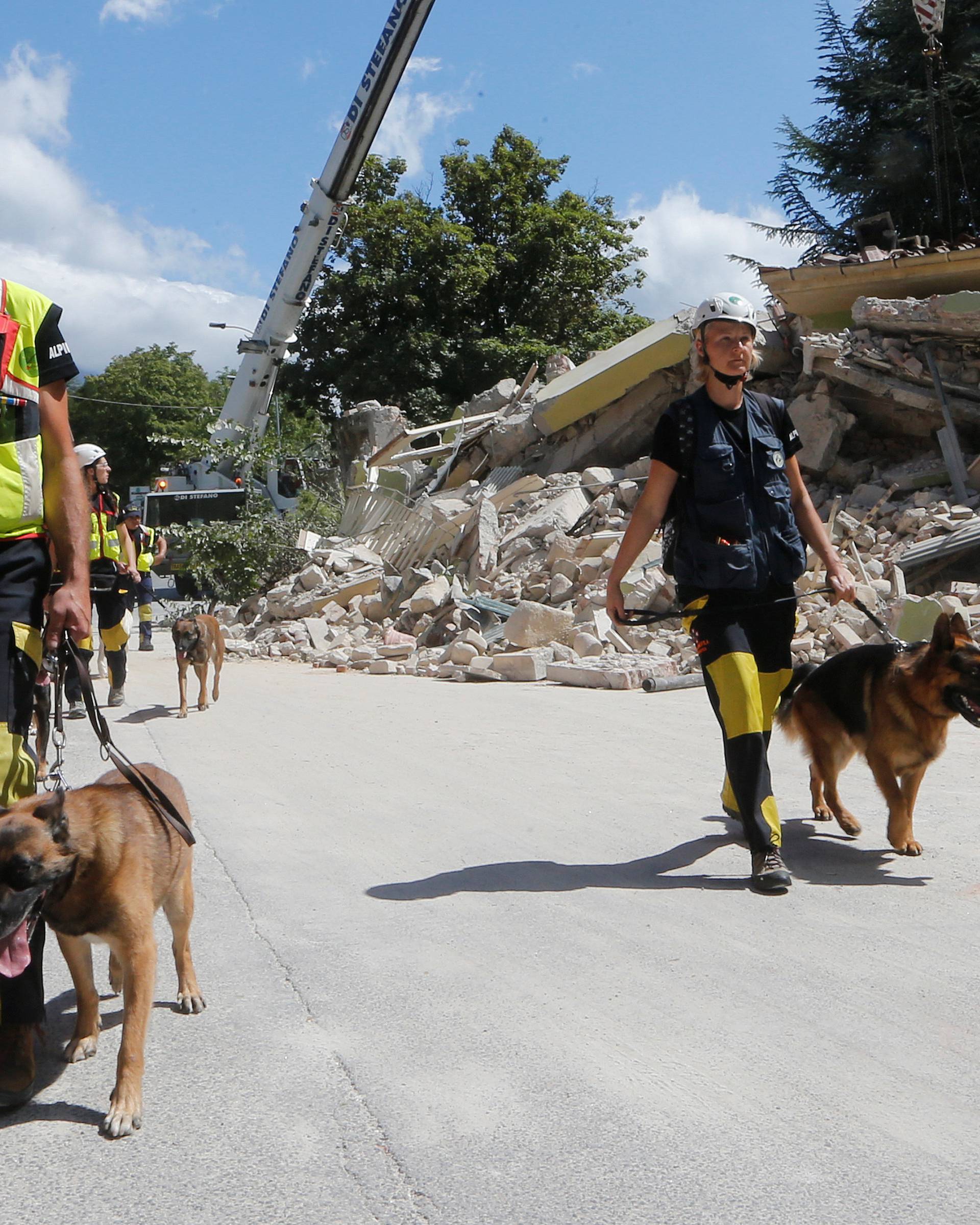 Rescuers walk with dogs following an earthquake in Amatrice