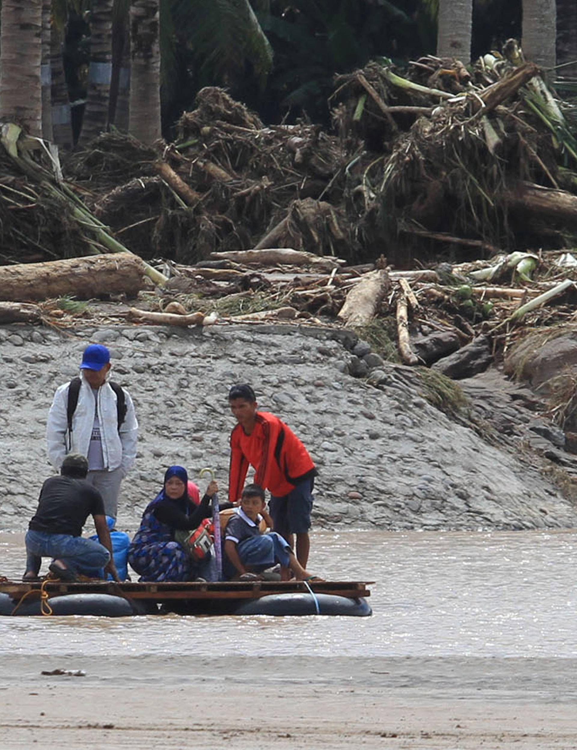Residents are transported on makeshift raft after bridge was destroyed during flash floods in Salvador, Lanao del Norte