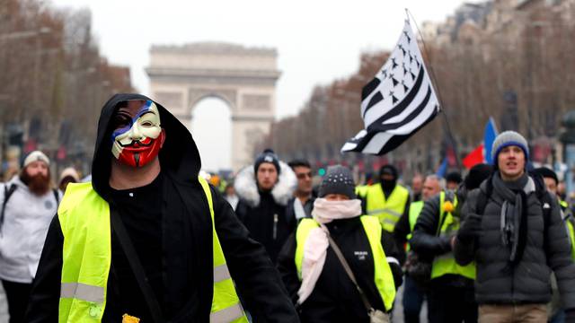 A protester wearing a yellow vest and an Anonymous mask takes part in a demonstration by the "yellow vests" movement in Paris