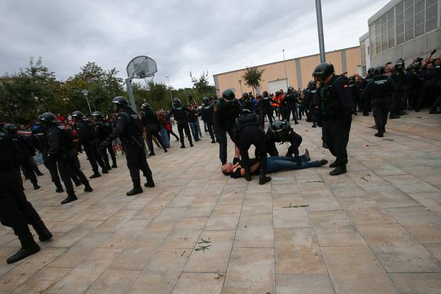 Spanish Civil Guard officers remove a man outside a polling station for the banned independence referendum in Sant Julia de Ramis
