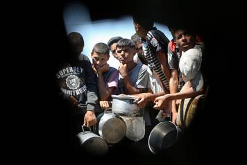 Palestinians wait to receive food from a charity kitchen, amid a hunger crisis, in Khan Younis