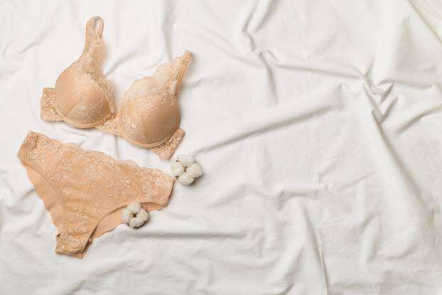 Flat Lay with women romantic underwear on white bed sheet, top view