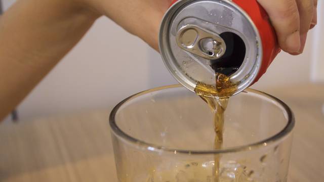 Woman fills the glass with cola