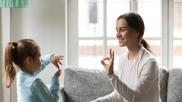 Young mom practice sign language with little daughter
