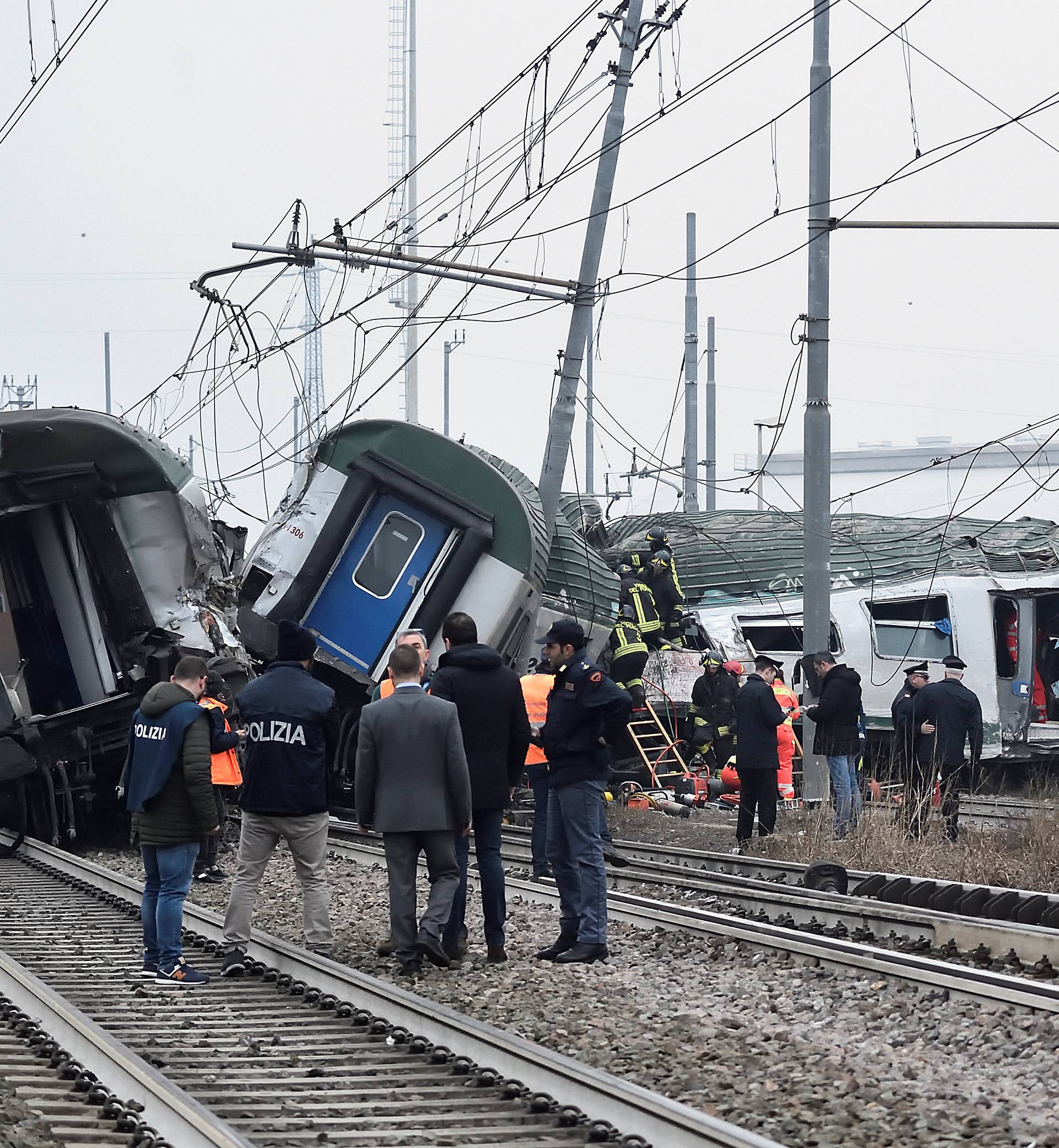Rescue workers and police officers stand near derailed trains in Pioltello, on the outskirts of Milan