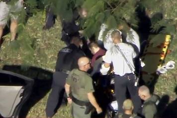 A man placed in handcuffs by police is loaded onto a stretcher near Marjory Stoneman Douglas High School following a shooting incident in Parkland