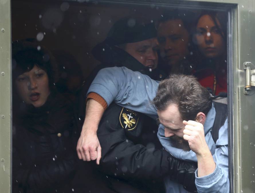 A law enforcement officer detains a man during a gathering which marks the anniversary of the proclamation of the Belarussian People's Republic in Minsk