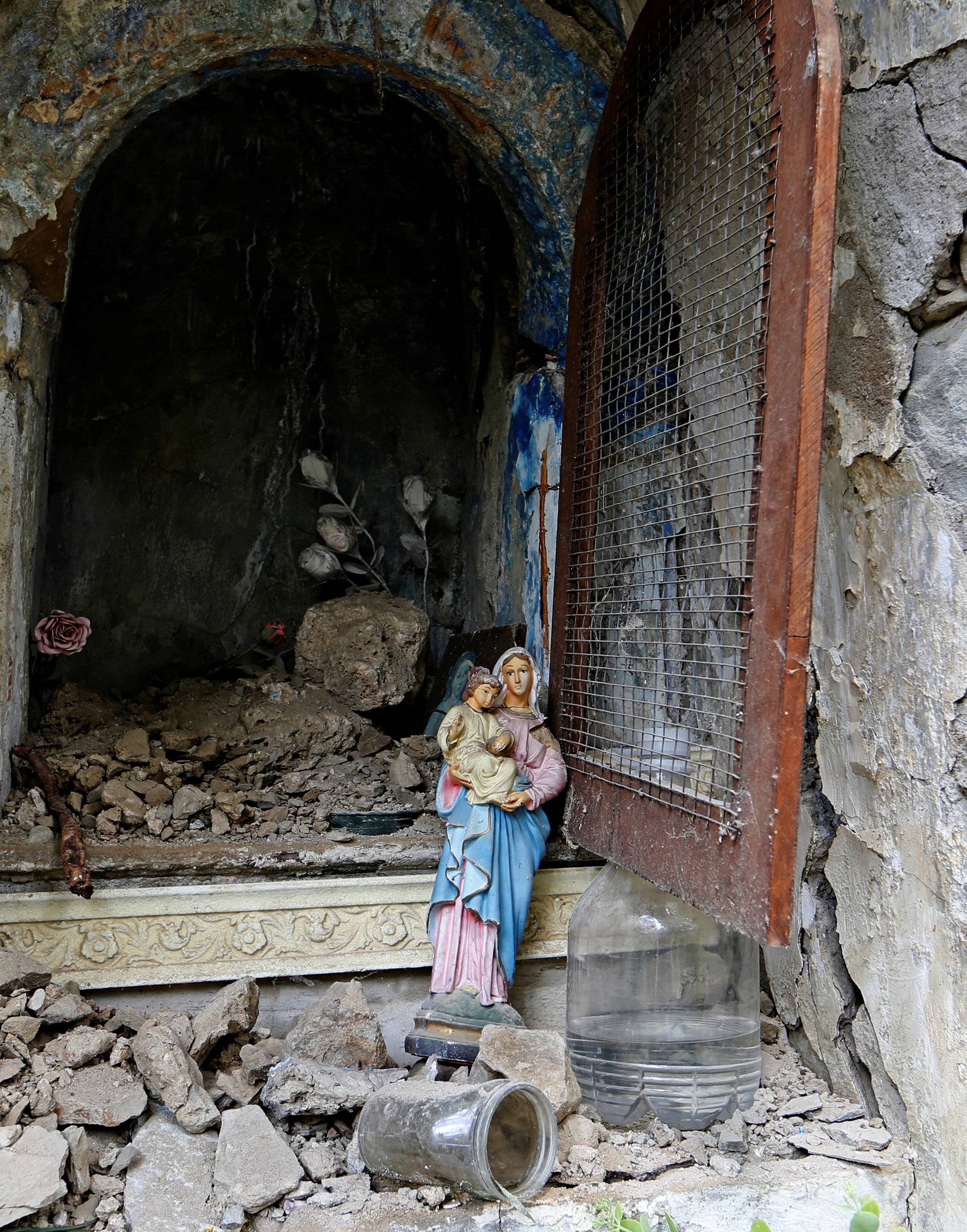 A statue of the Virgin Lady stands outside a destroyed niche following an earthquake at Pescara del Tronto