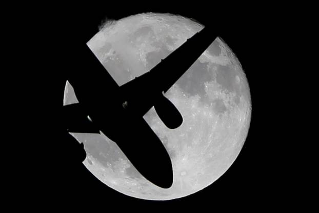 A Vueling passenger aircraft flies past a super moon in Ardales