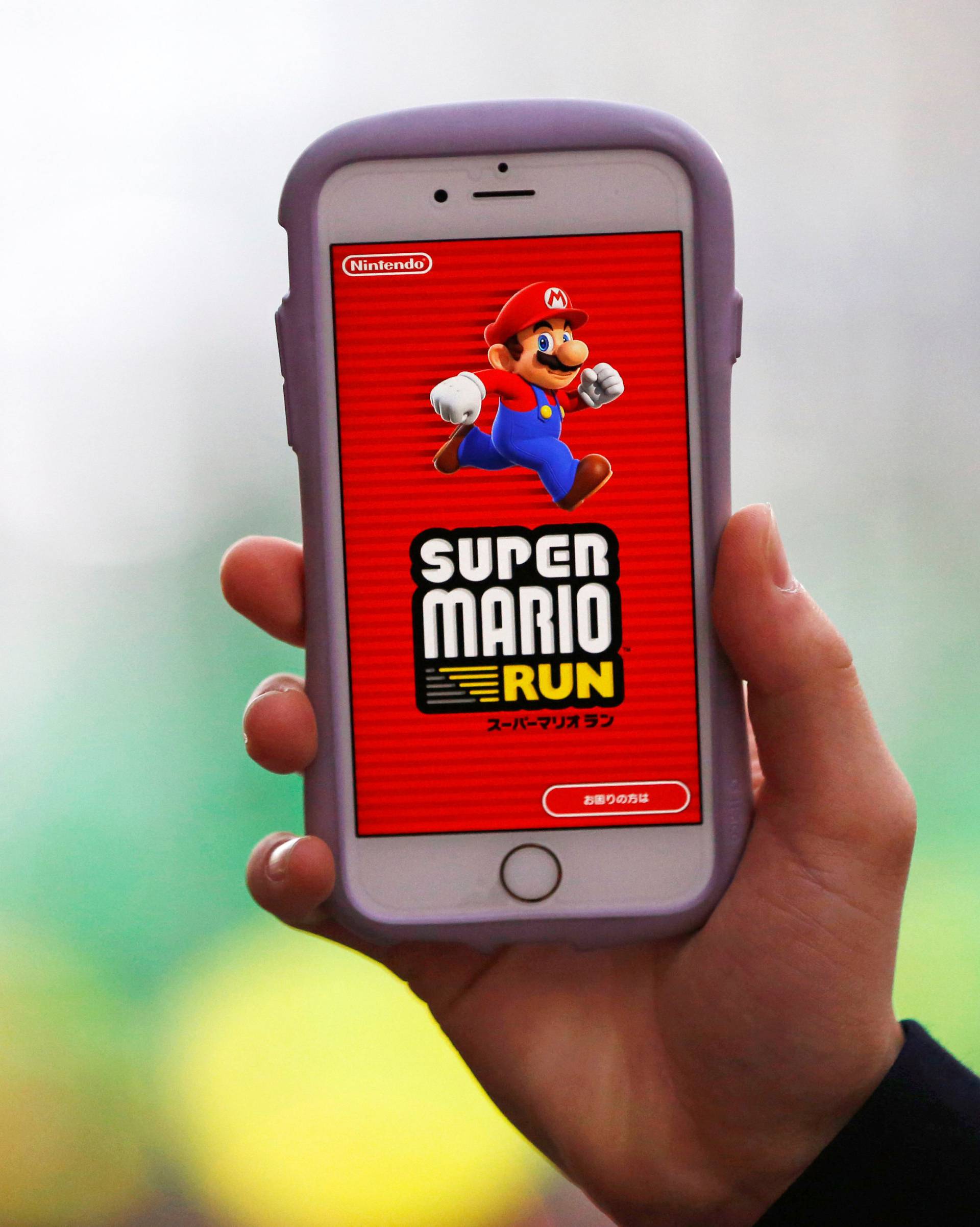 A person poses to display Nintendo's "Super Mario Run" game on a mobile phone in Tokyo, Japan