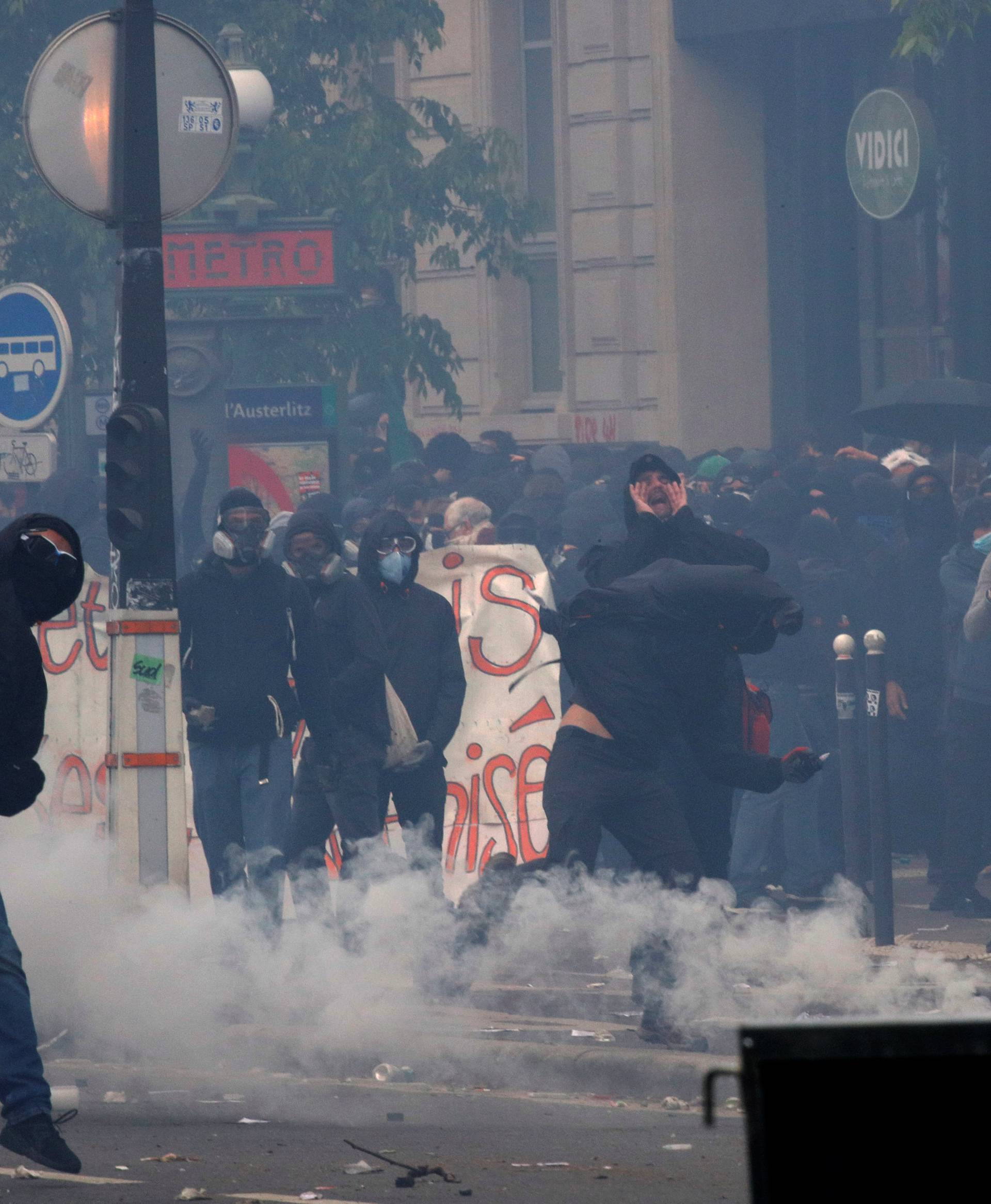 A masked protester throws a rock during clashes at the May Day labour union march in Paris