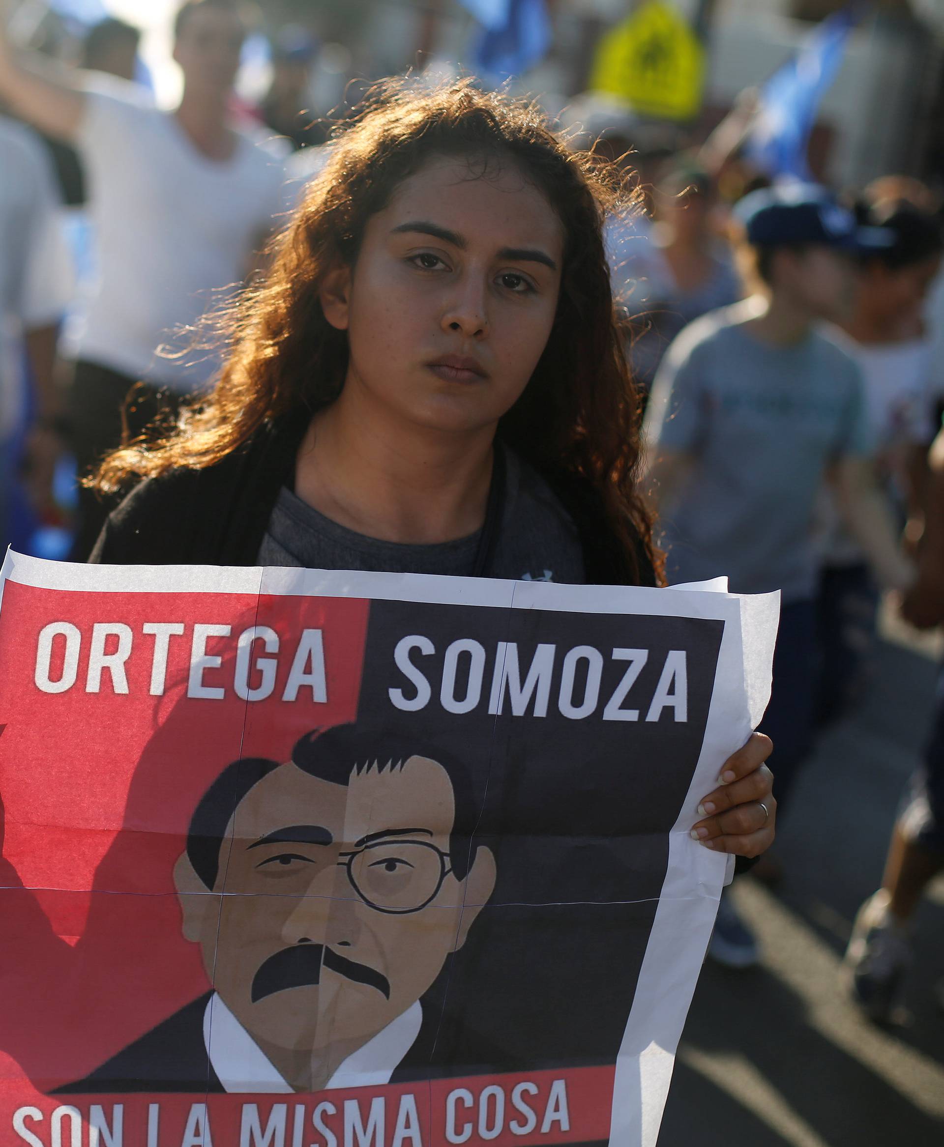 A demonstrator holds a sign showing Nicaraguan President Daniel Ortega and former President Anastasio Somoza during a protest against police violence and the government of President Ortega in Managua