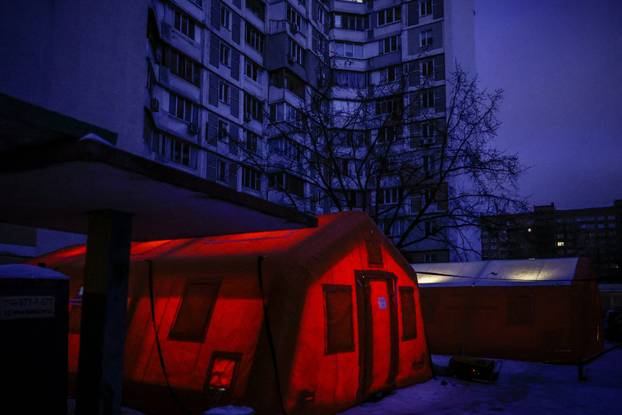 People warm up and charge their devices inside a temporary shelter, which offers basic services and heat during blackouts, in Kyiv