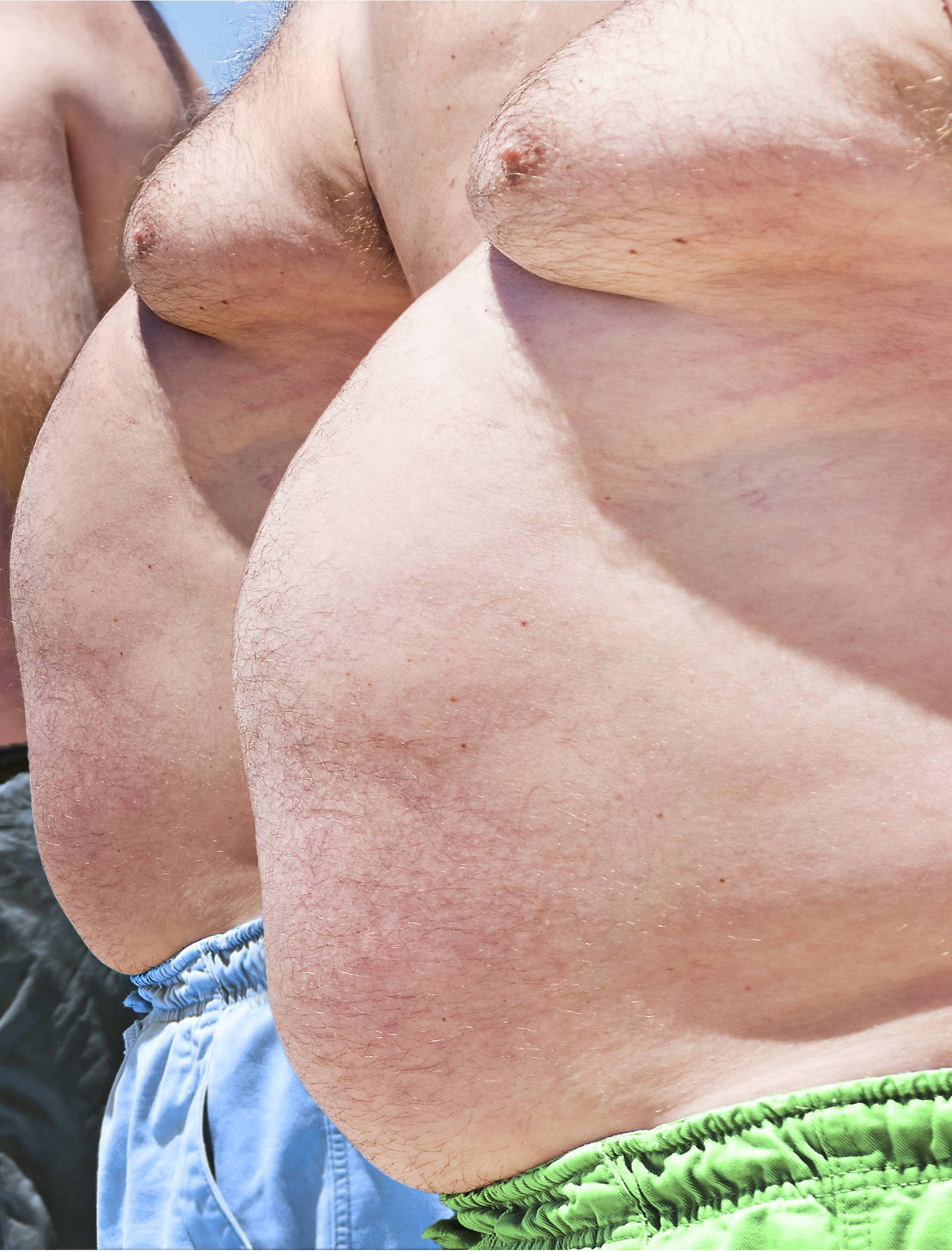 Close up of three obese fat men of the beach