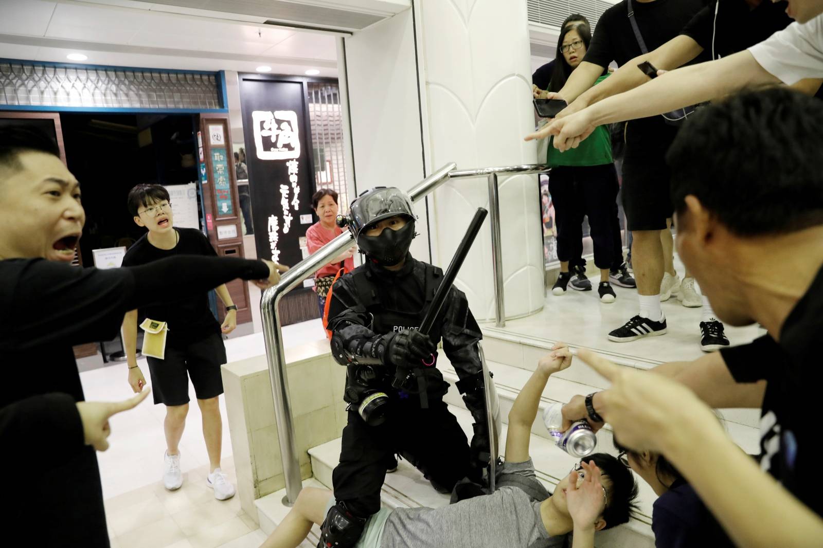 Riot police officer detains a protester at a shopping mall in Tai Po in Hong Kong