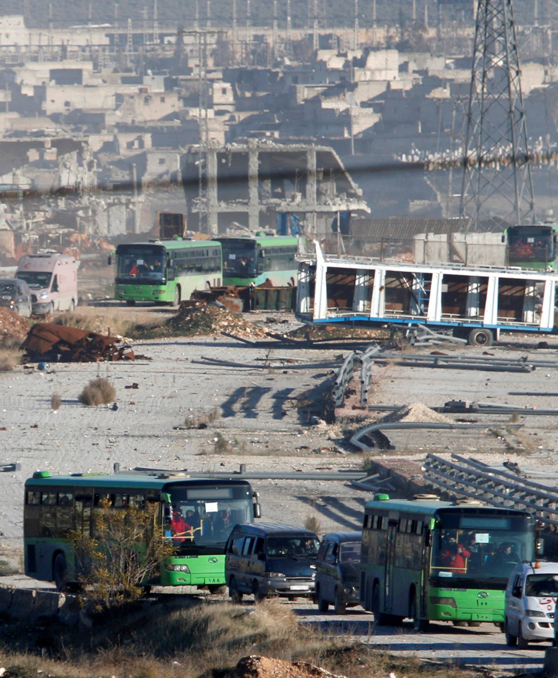 Ambulances and buses evacuating people drive out of a rebel-held part of Aleppo