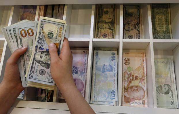 FILE PHOTO - A money changer counts U.S. dollar bills, with Turkish lira banknotes in the background, at an currency exchange office in central Istanbul