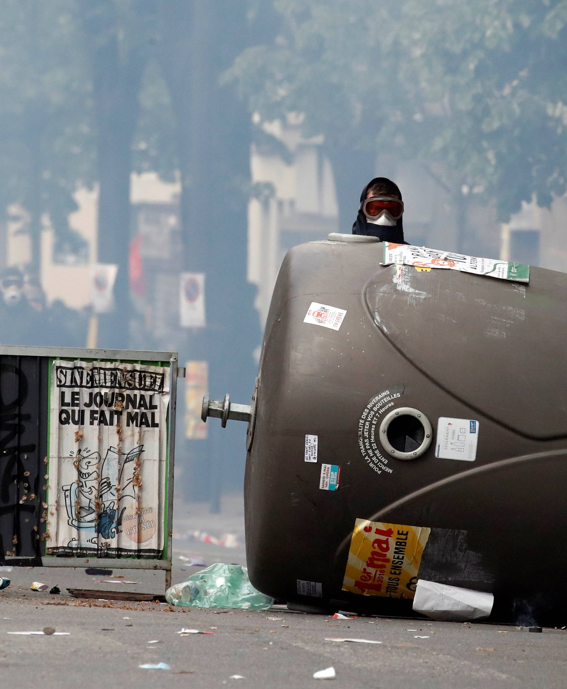 Masked protesters take cover during clashes with French riot police at the May Day labour union rally in Paris