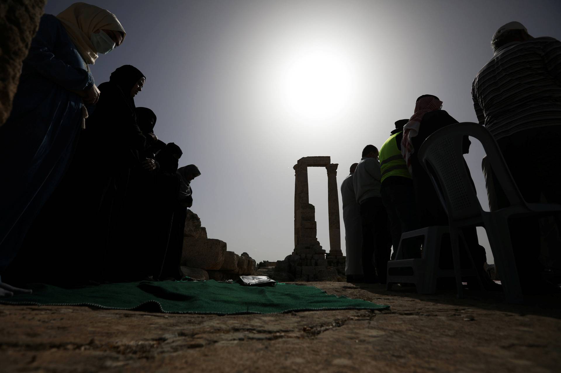 Muslim men perform mass prayers during a partial solar eclipse at the Amman Citadel, an ancient Roman landmark, in Amman