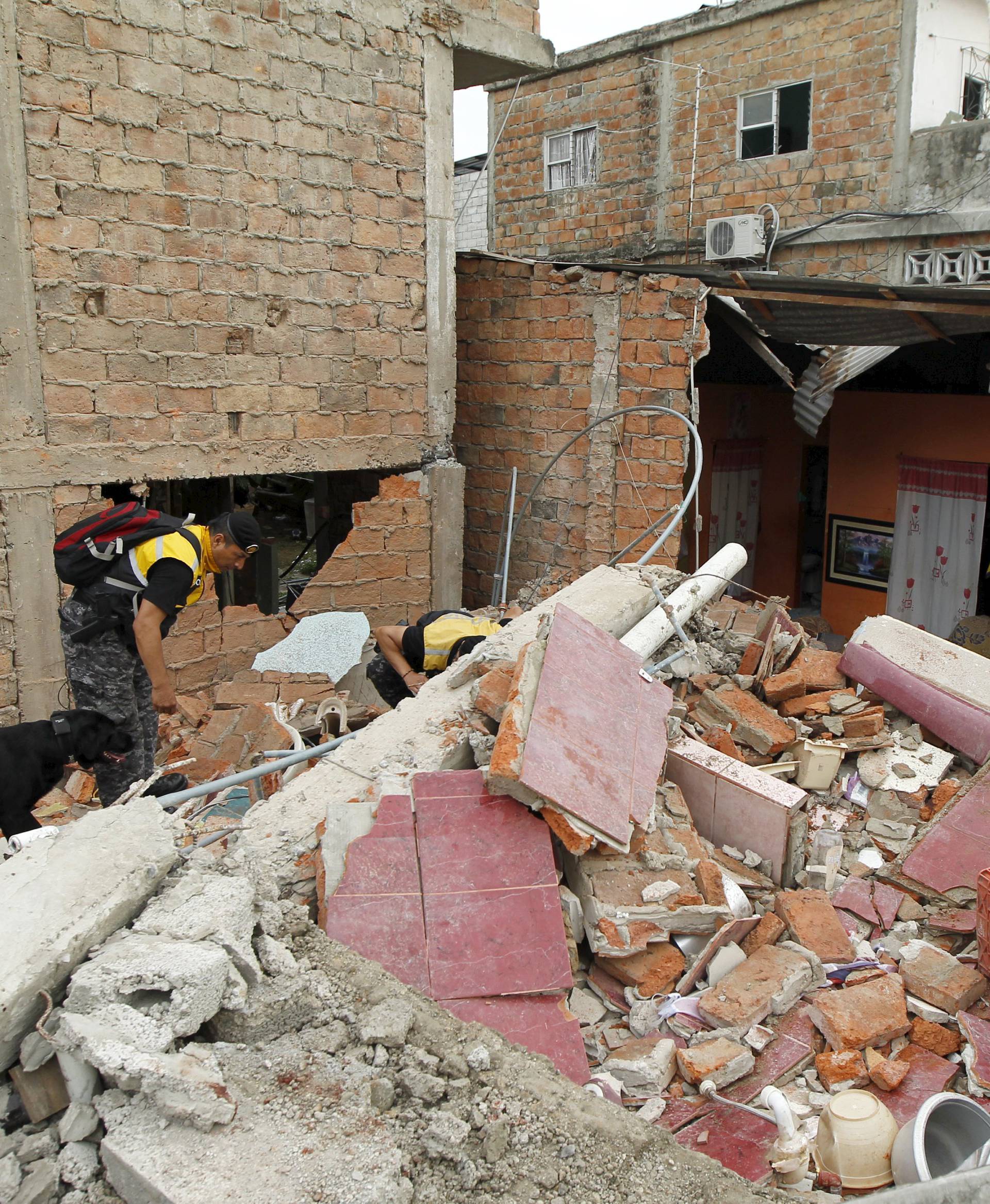 Police officers search through debris after an earthquake struck off Ecuador's Pacific coast, at Tarqui neighborhood in Manta
