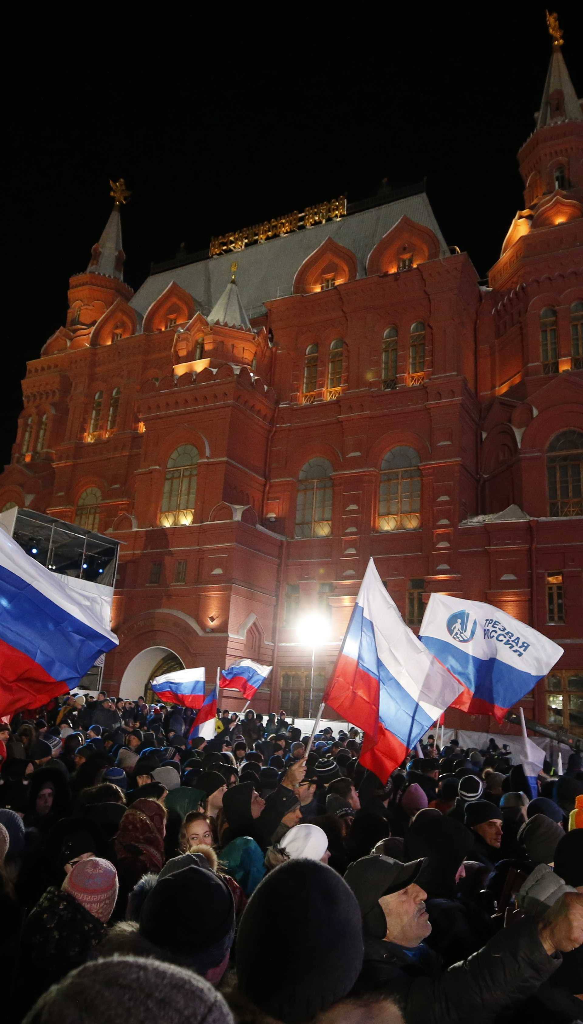 People wave Russian flags during a rally and concert marking the fourth anniversary of Russia's annexation of the Crimea region, at Manezhnaya Square in central Moscow