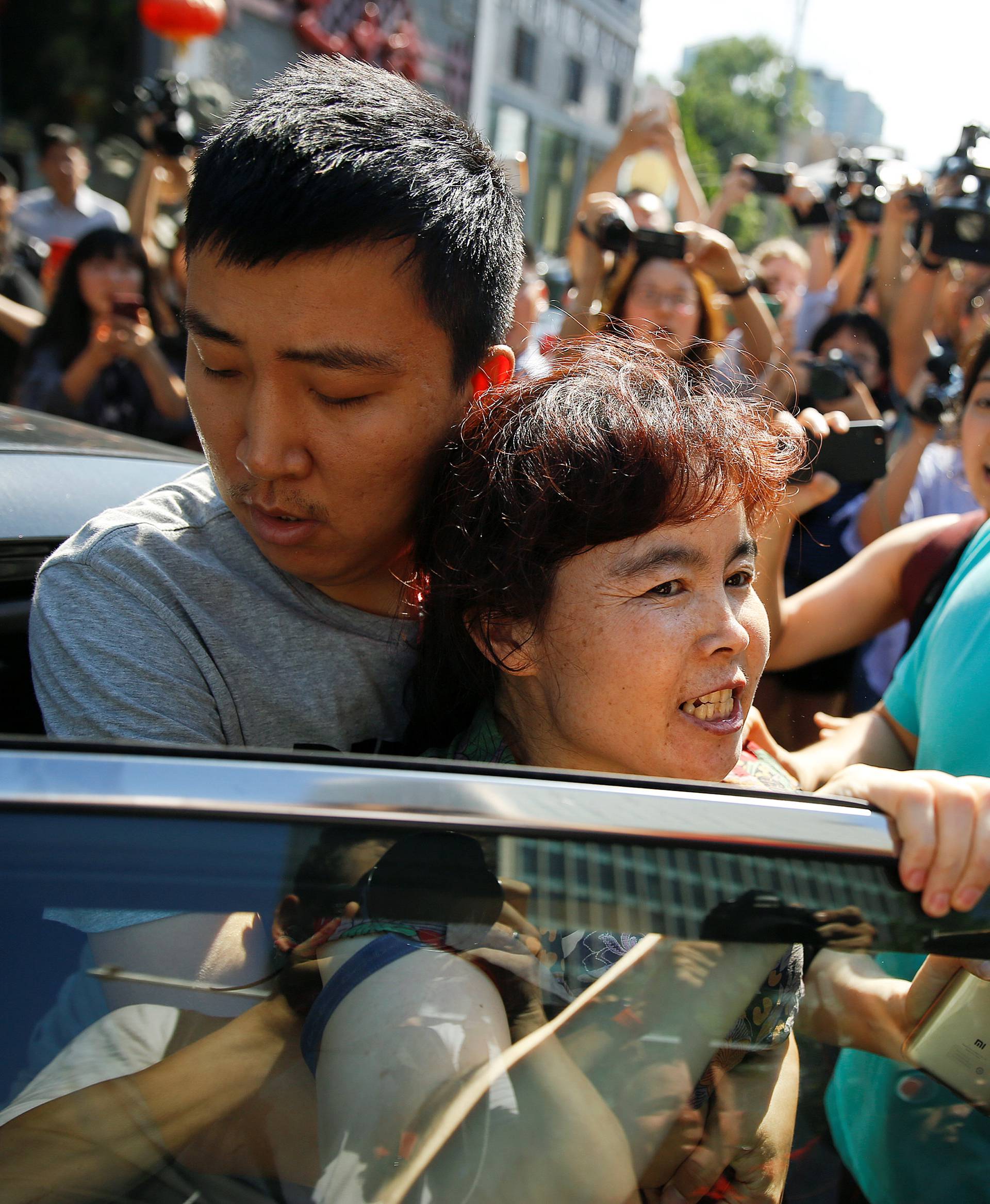 A woman is detained by security personnel outside the U.S. embassy in Beijing