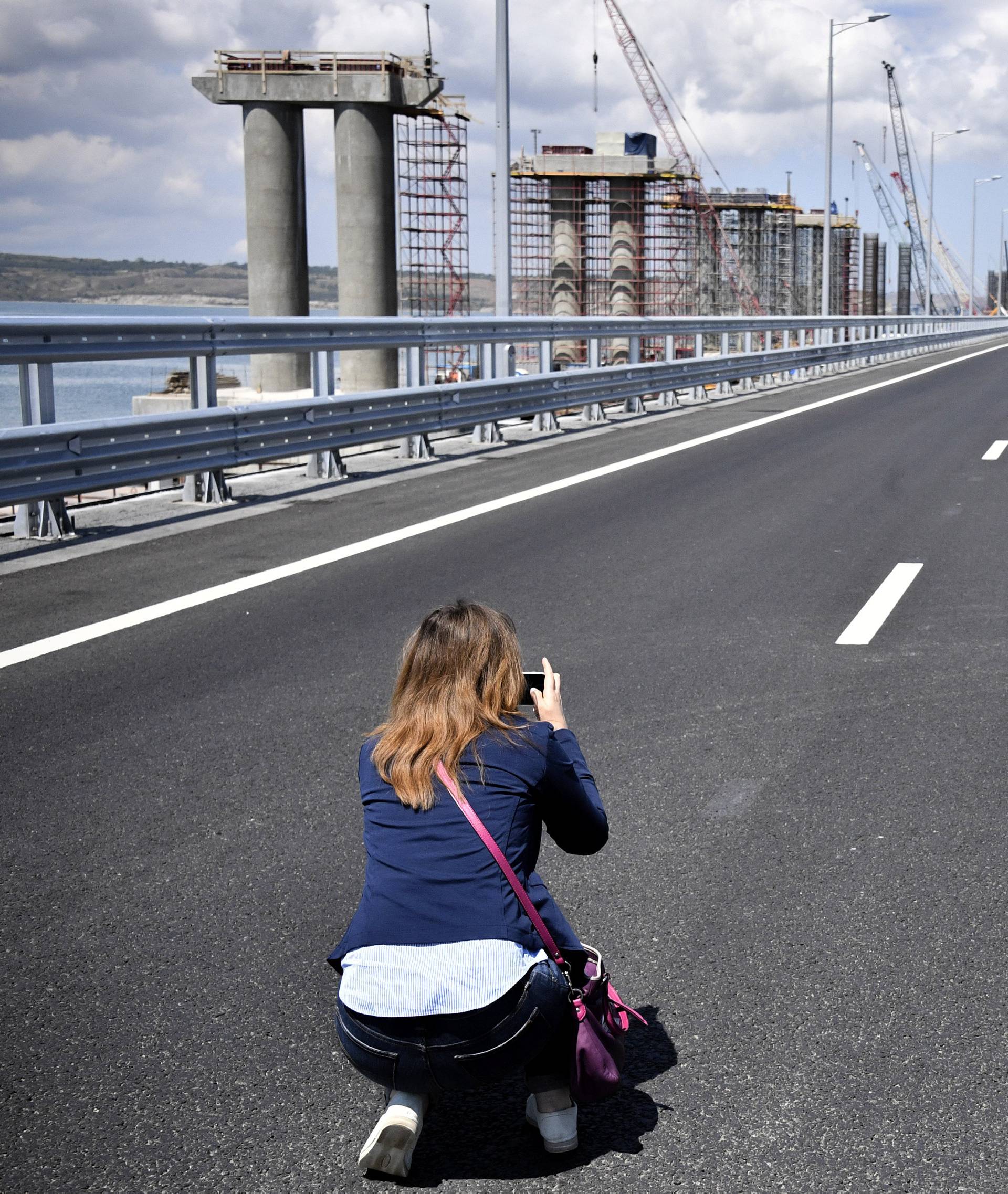 A woman takes pictures prior to a ceremony opening a bridge, which was constructed to connect the Russian mainland with the Crimean Peninsula across the Kerch Strait