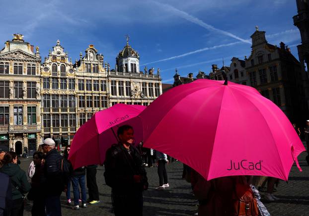 Tour guides hold pink umbrellas while waiting for tourists at Brussels' Grand Place in Brussels