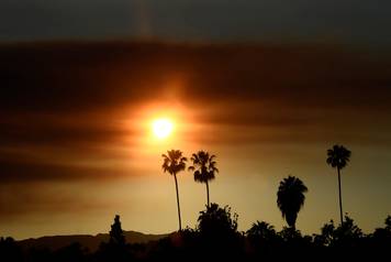 As seen from the San Fernando Valley of Los Angeles, the sun set behind a smokey sky caused by the "Old Fire", which burned in Calabasas, California