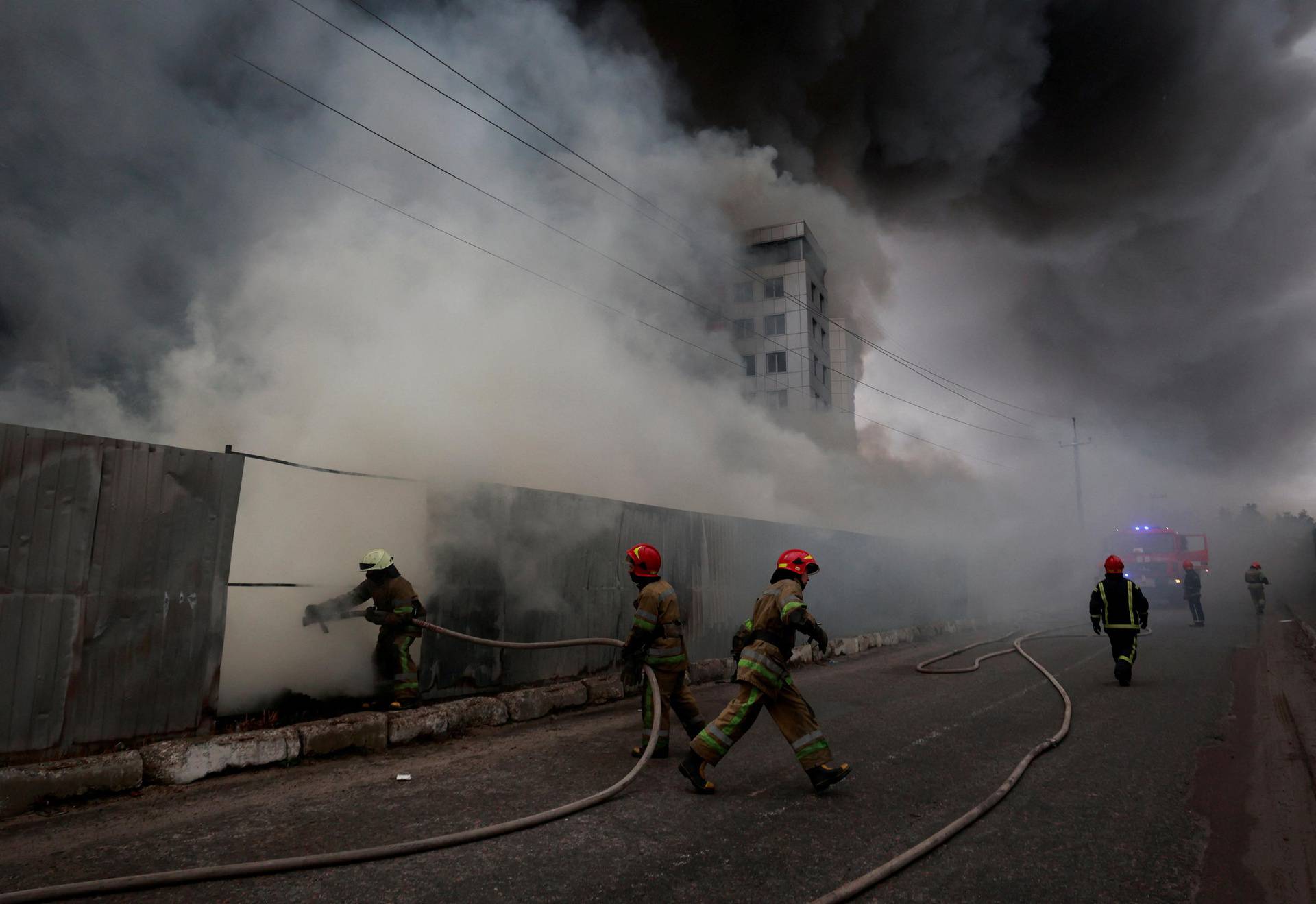 Firefighters extinguish fire at a warehouse that caught flames, according to local authorities, after shelling, in the Kyiv region