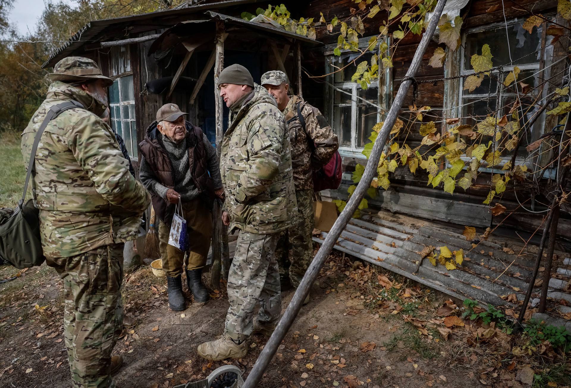 Ivan Troyanok speaks with servicemen near his house in a Chornobyl exclusion zone village