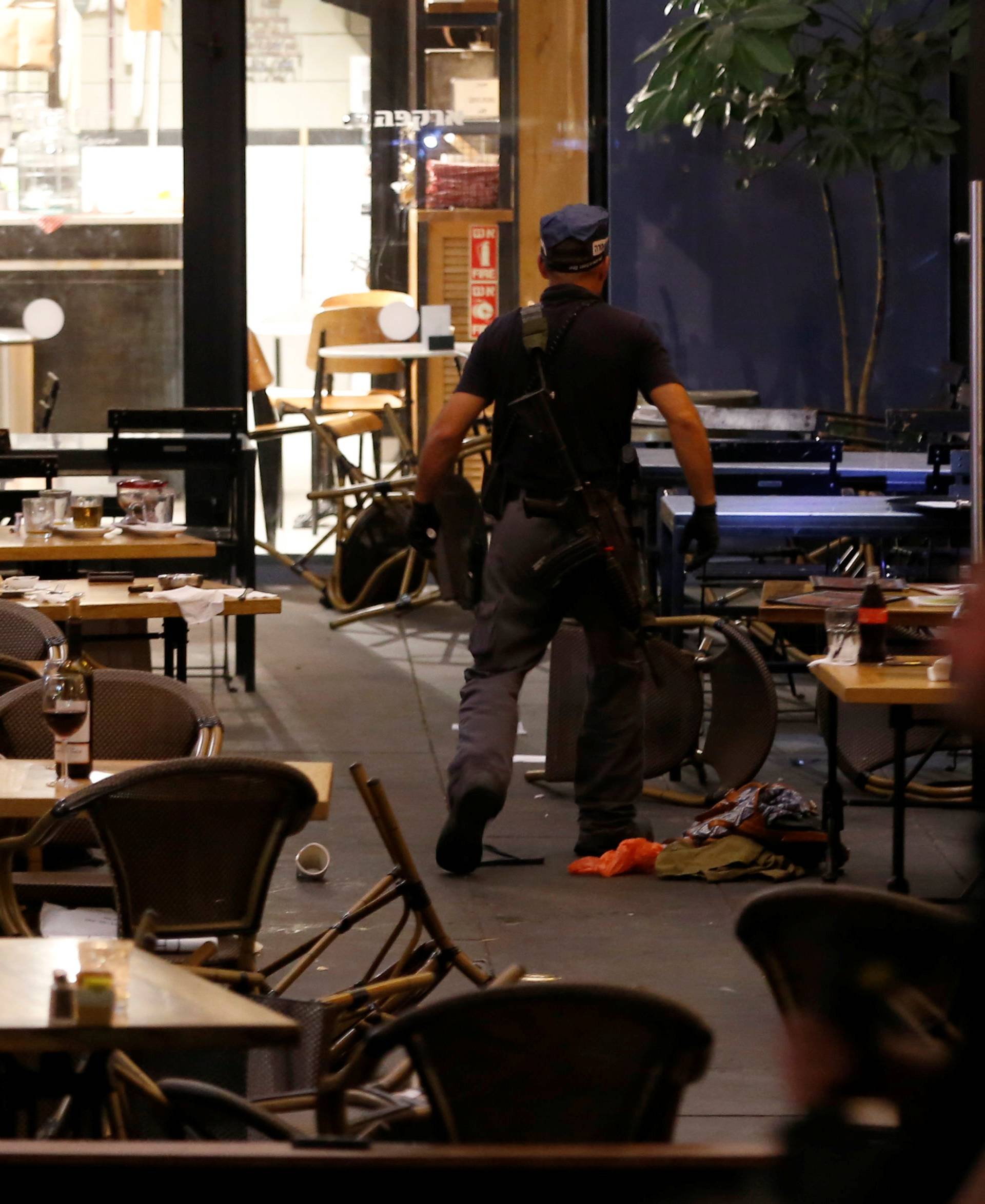 An Israeli policeman searches a restaurant following a shooting attack in the center of Tel Aviv