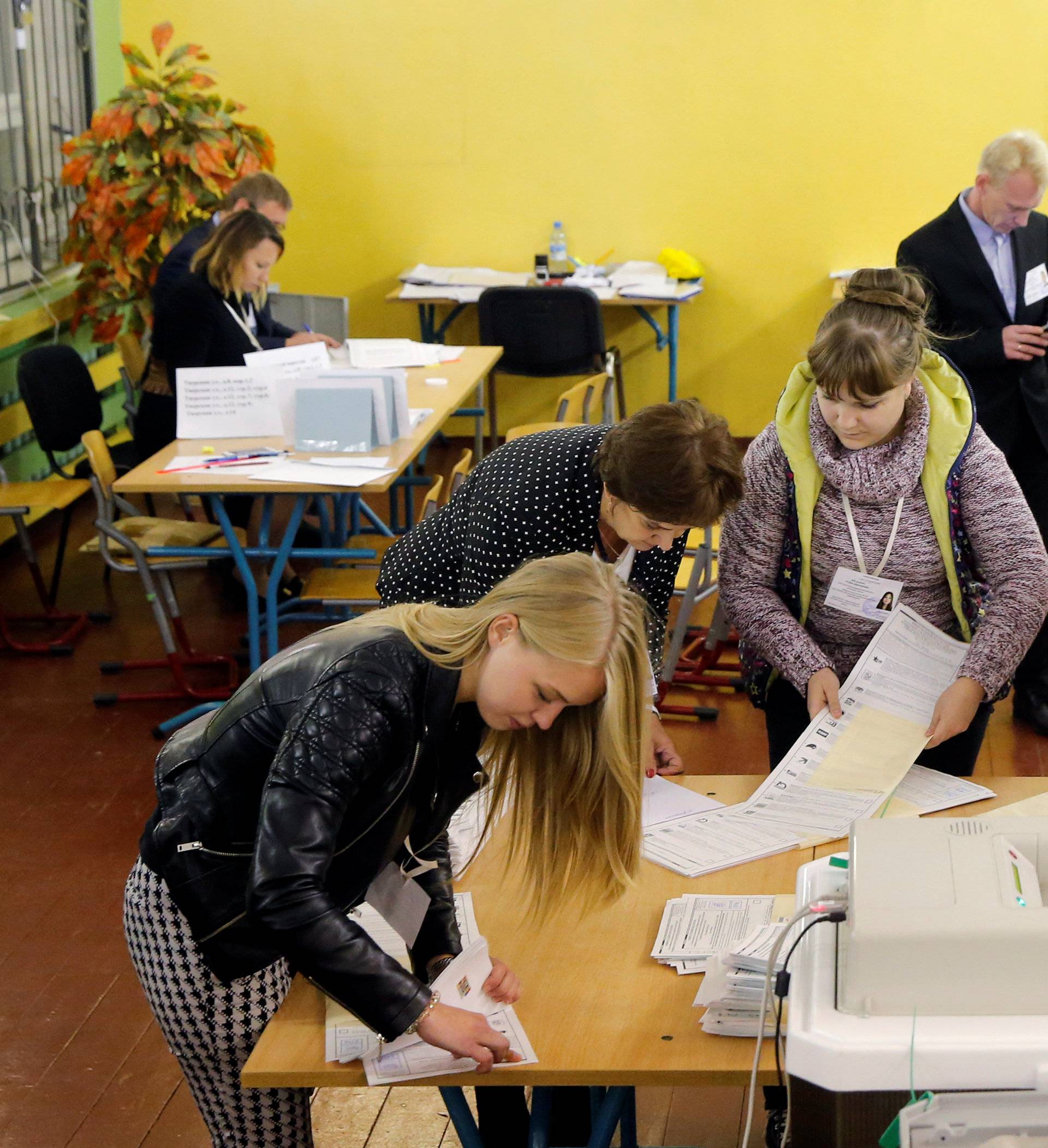 Members of a local election commission count unused ballots at a polling station following a parliamentary election in Moscow
