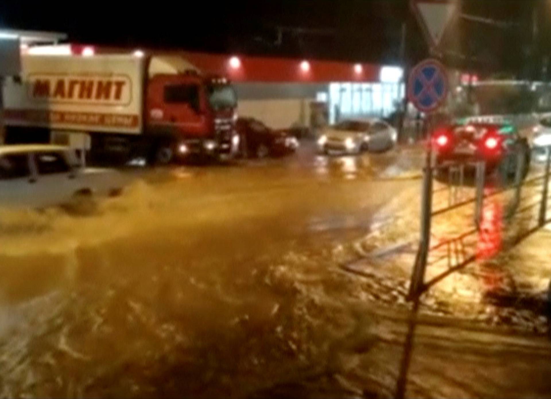 A still image shows vehicles driving along a street in a settlement affected by floodwaters in Krasnodar Region