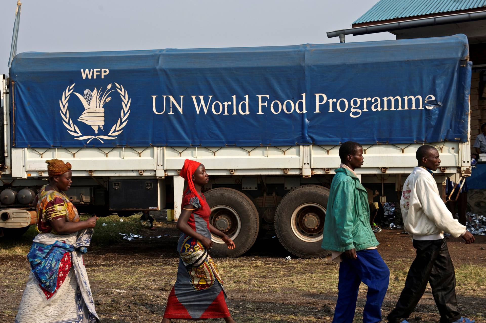 FILE PHOTO: Displaced Congolese civilians walk past a truck carrying food for distribution at Kibati, just outside the eastern Congolese city of Goma