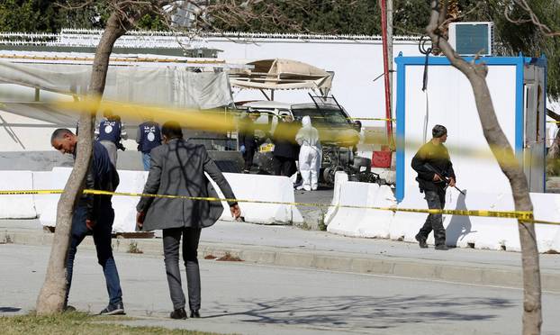 A forensic expert and police officers are seen at the site of a suicide attack near the U.S. embassy in Tunis