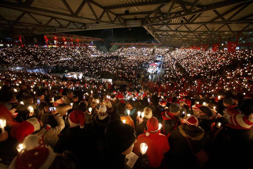 People attend the "Weihnachtssingen", a candle-lit carol concert at the Alte Foersterei stadium in Berlin