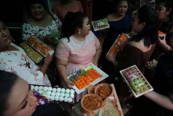 Participants in the Miss Jumbo beauty contest hold up desserts at a dessert shop in Nakhon Ratchasima
