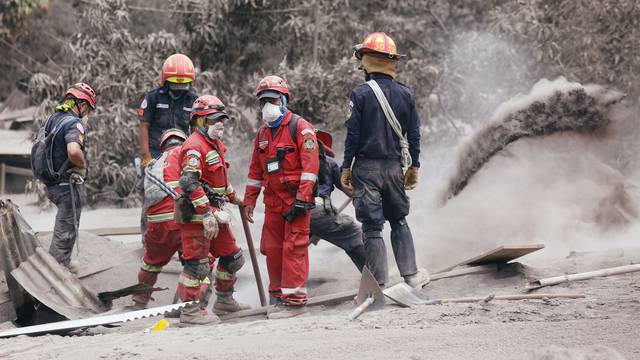 Rescue workers remove ash at an area affected by the eruption of the Fuego volcano in the community of San Miguel Los Lotes in Escuintla