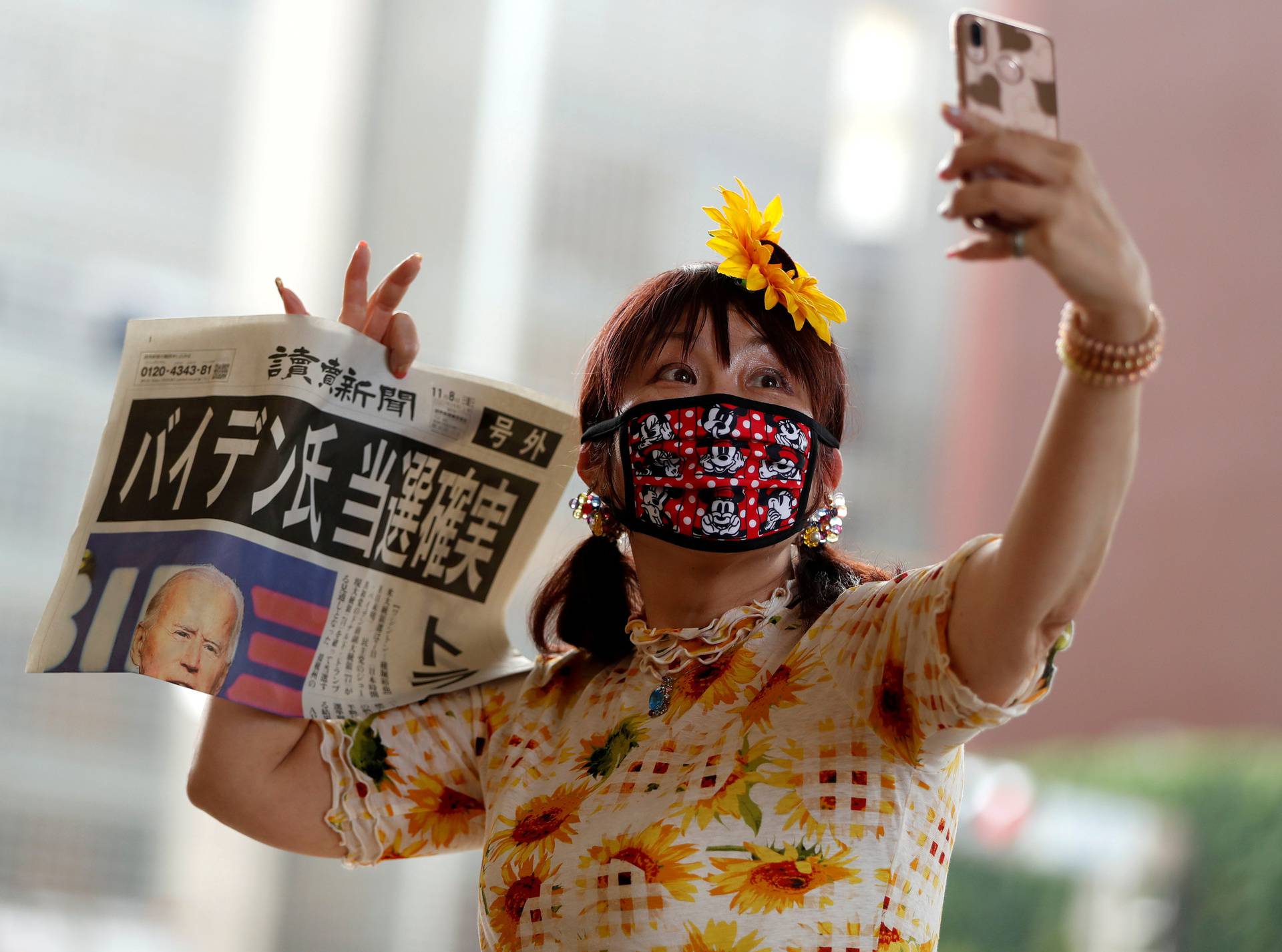 A woman takes selfie photo posing with an extra edition of a newspaper reporting that Democratic U.S. presidential nominee Joe Biden is projected to win the 2020 U.S. presidential election, in Tokyo